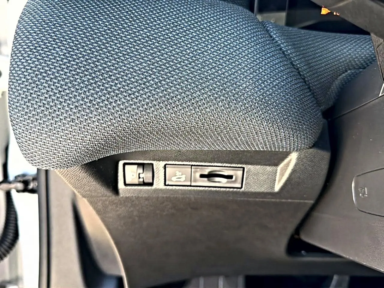 Détail des commandes de réglage lombaire sous le siège conducteur en tissu gris du Citroën C5 Aircross hybride 2026.
