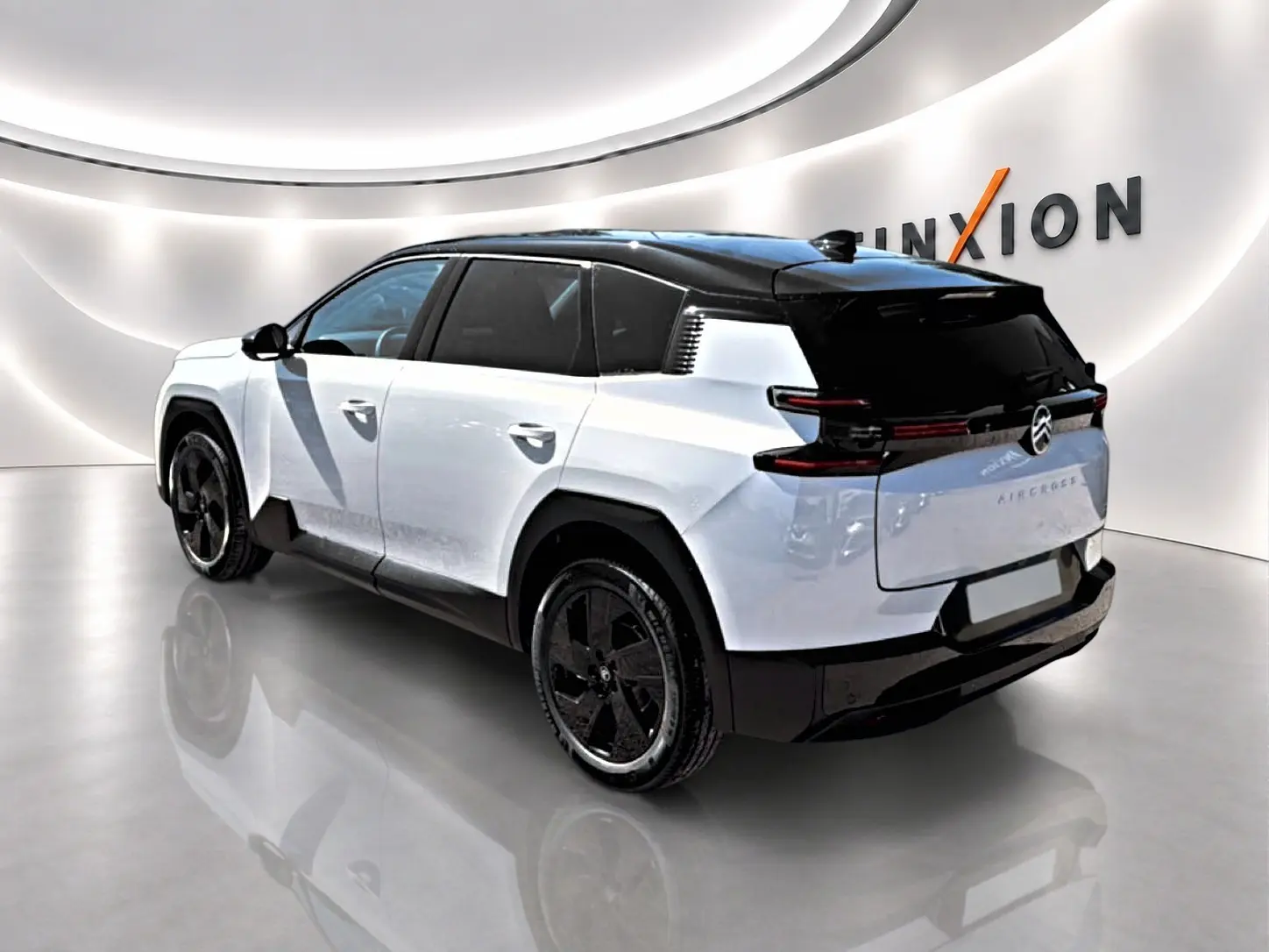 Vue 3/4 arrière droite du Citroën C5 Aircross blanc et noir avec jantes alliage noires dans un showroom lumineux.