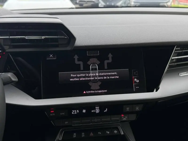 Vue rapprochée de l’écran central tactile et de la console de l’Audi A3 Sportback 2024 avec affichage d’aide au stationnement.