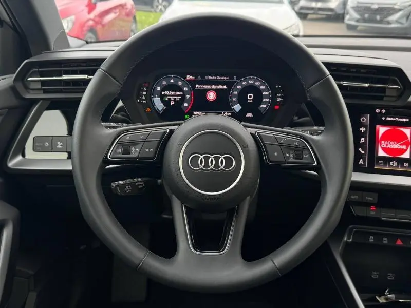 Vue frontale du volant en cuir multifonction de l'Audi A3 Sportback 2024 avec tableau de bord numérique et écran central allumé.
