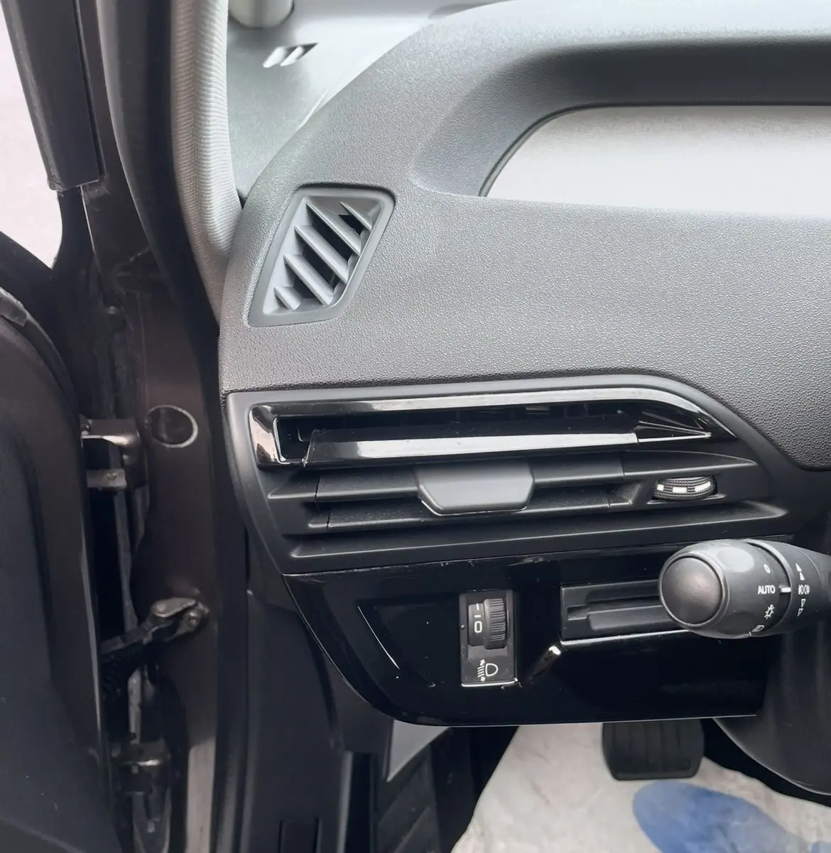 Détail de la console côté gauche d'une Citroën C4 Picasso marron, montrant les aérateurs et commandes d'éclairage.