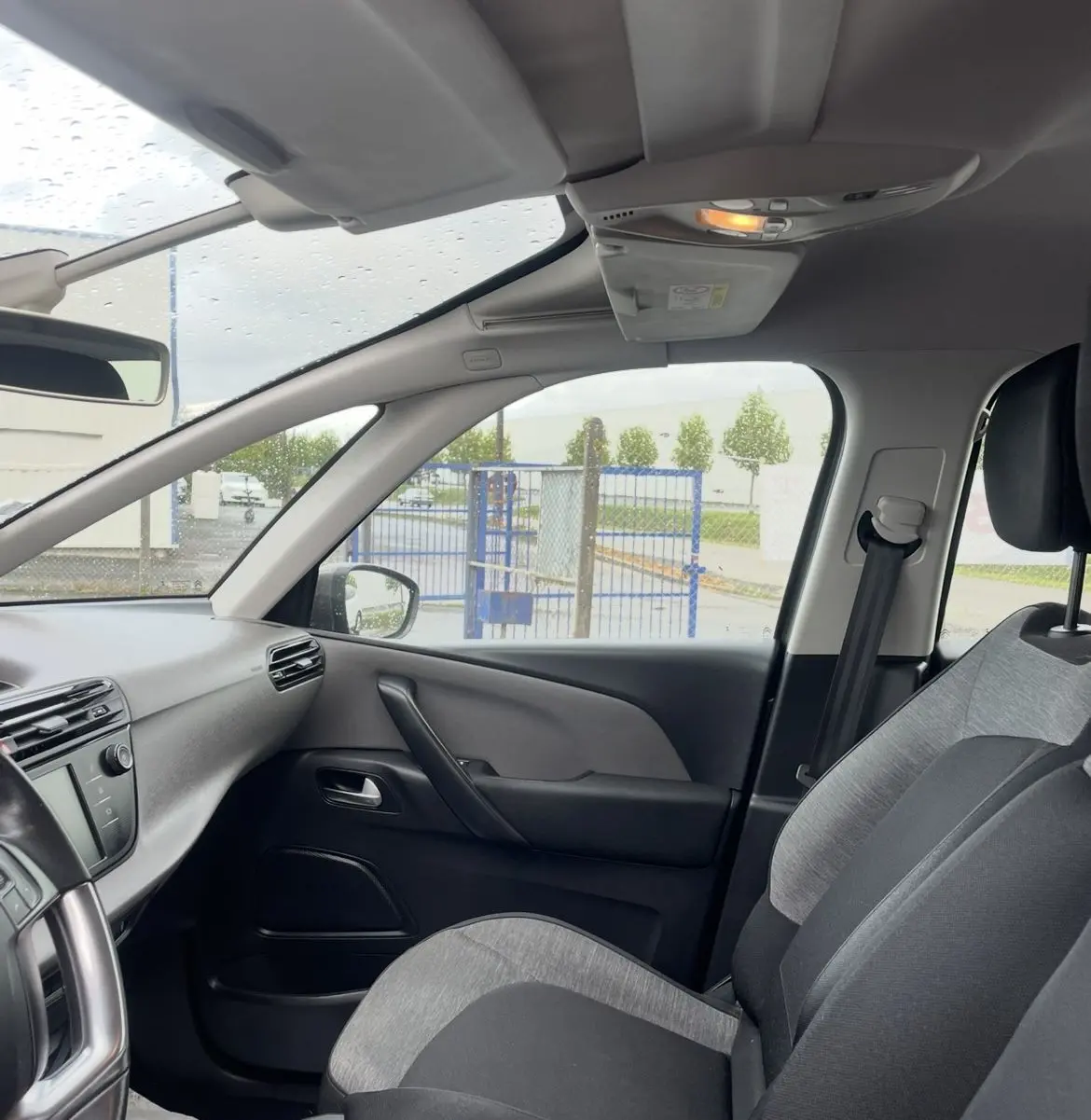 Vue intérieure côté passager avant d'une Citroën C4 Picasso 2017, sièges gris et noir avec tableau de bord visible.