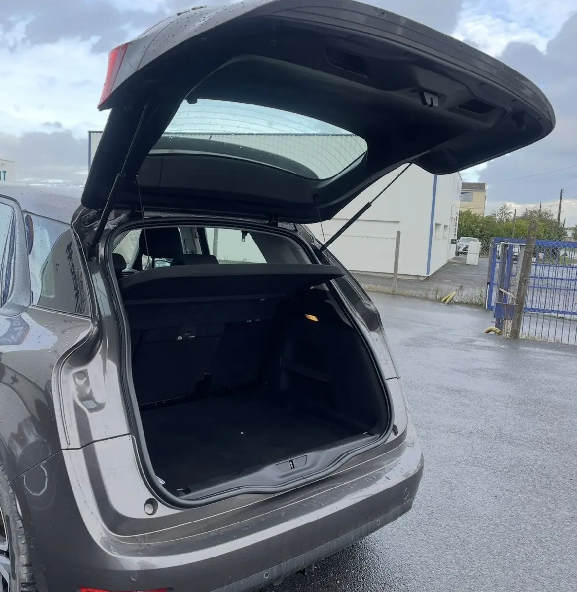 CITROEN C4 PICASSO marron vu de l'arrière avec le coffre ouvert, montrant l'espace de chargement vide.