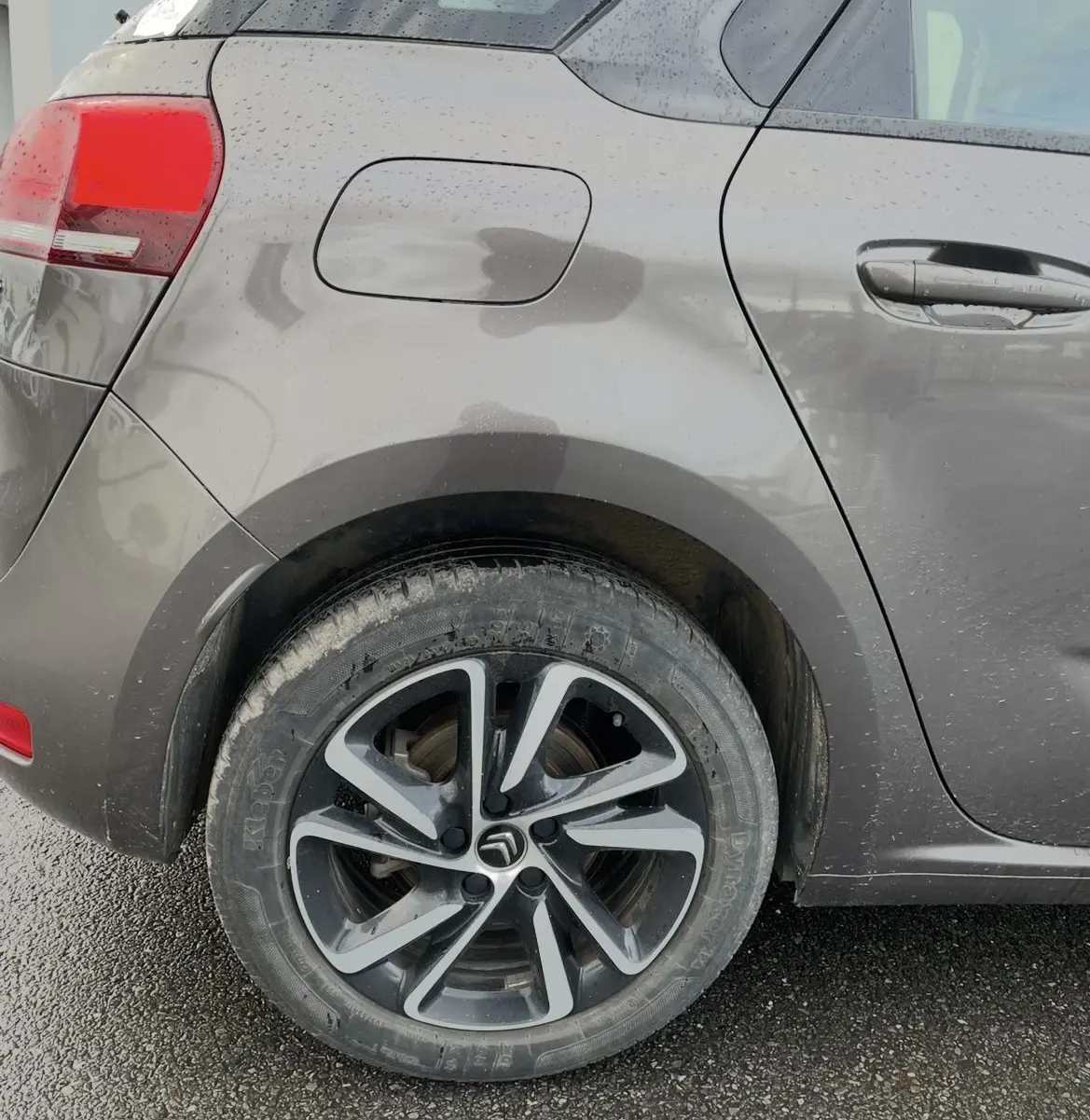 Gros plan sur la roue arrière gauche et la portière marron d'une Citroën C4 Picasso avec jante alu au design moderne.