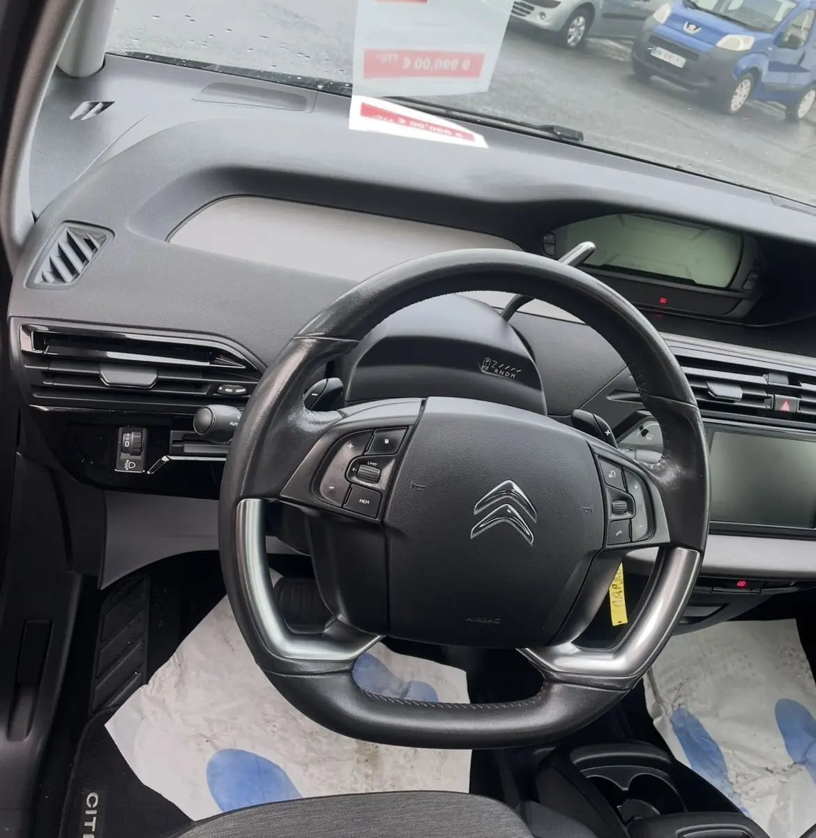 Vue intérieure centrée sur le volant cuir multifonction d'une Citroën C4 Picasso 2017, tableau de bord et écran tactile visibles.