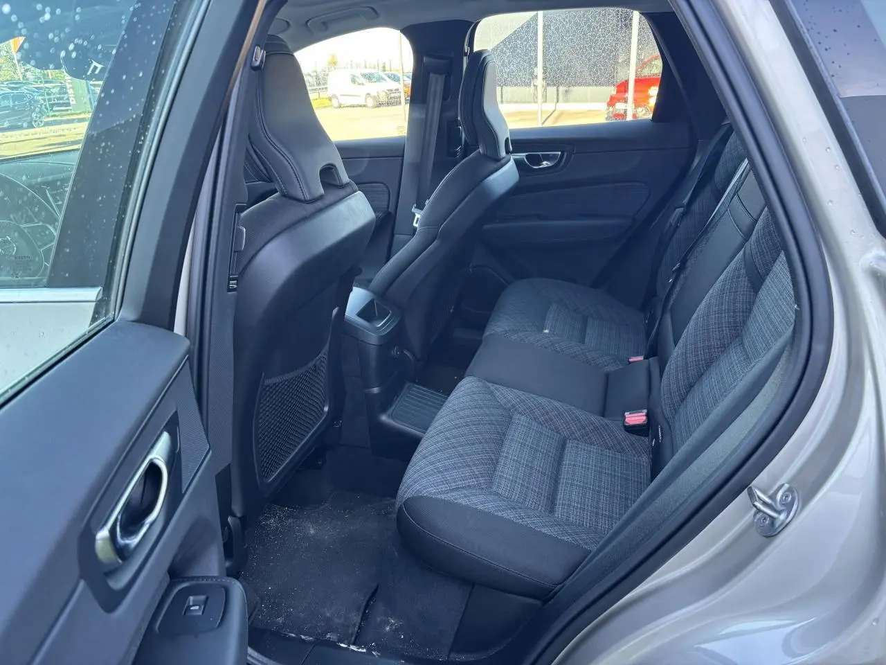 Vue intérieure côté arrière droit du Volvo XC60 2024 argent crépuscule, montrant les sièges arrière en tissu gris à motifs.