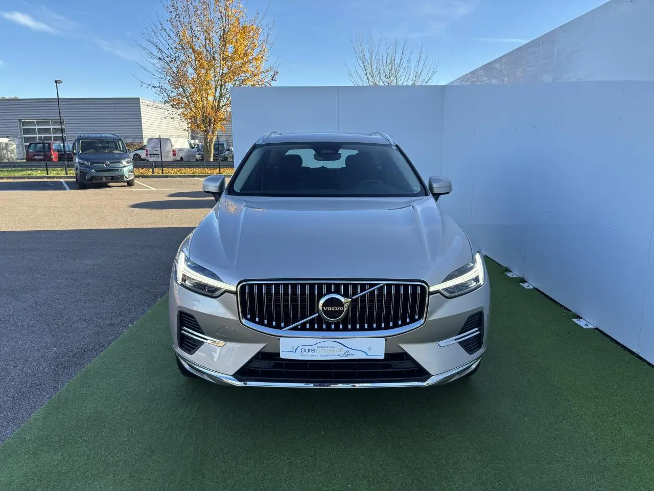Vue frontale d'un Volvo XC60 2024 argent crépuscule métallisé avec calandre verticale et phares LED allumés.