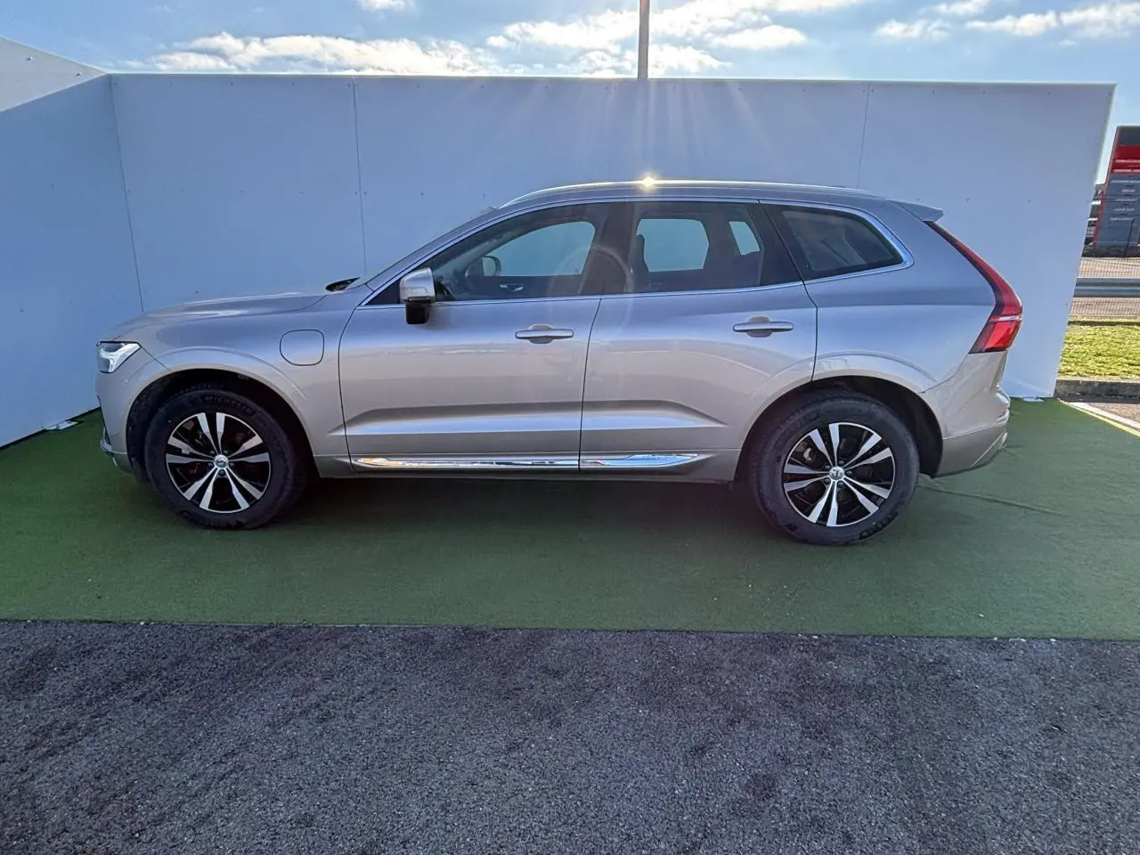 Volvo XC60 T6 Recharge argent crépuscule métal vu de profil côté gauche avec jantes alliage et toit panoramique.