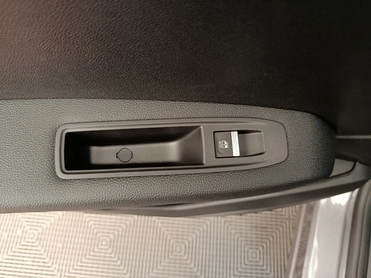 Bouton de lève-vitre électrique sur la porte côté droit du Renault Captur gris foncé 2025 en vue rapprochée.