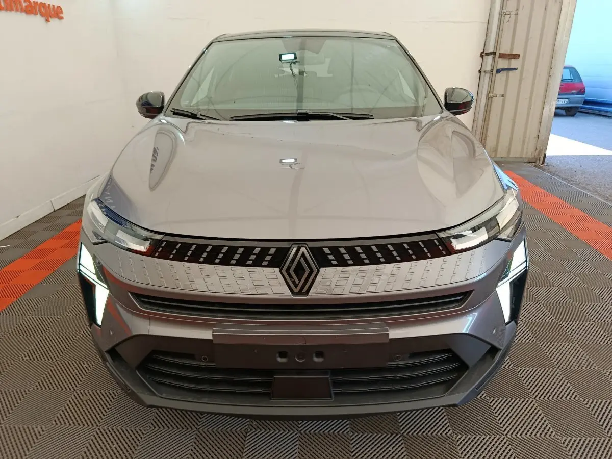 Vue frontale d'un Renault Captur gris foncé 2025 avec phares LED allumés et calandre moderne distinctive.