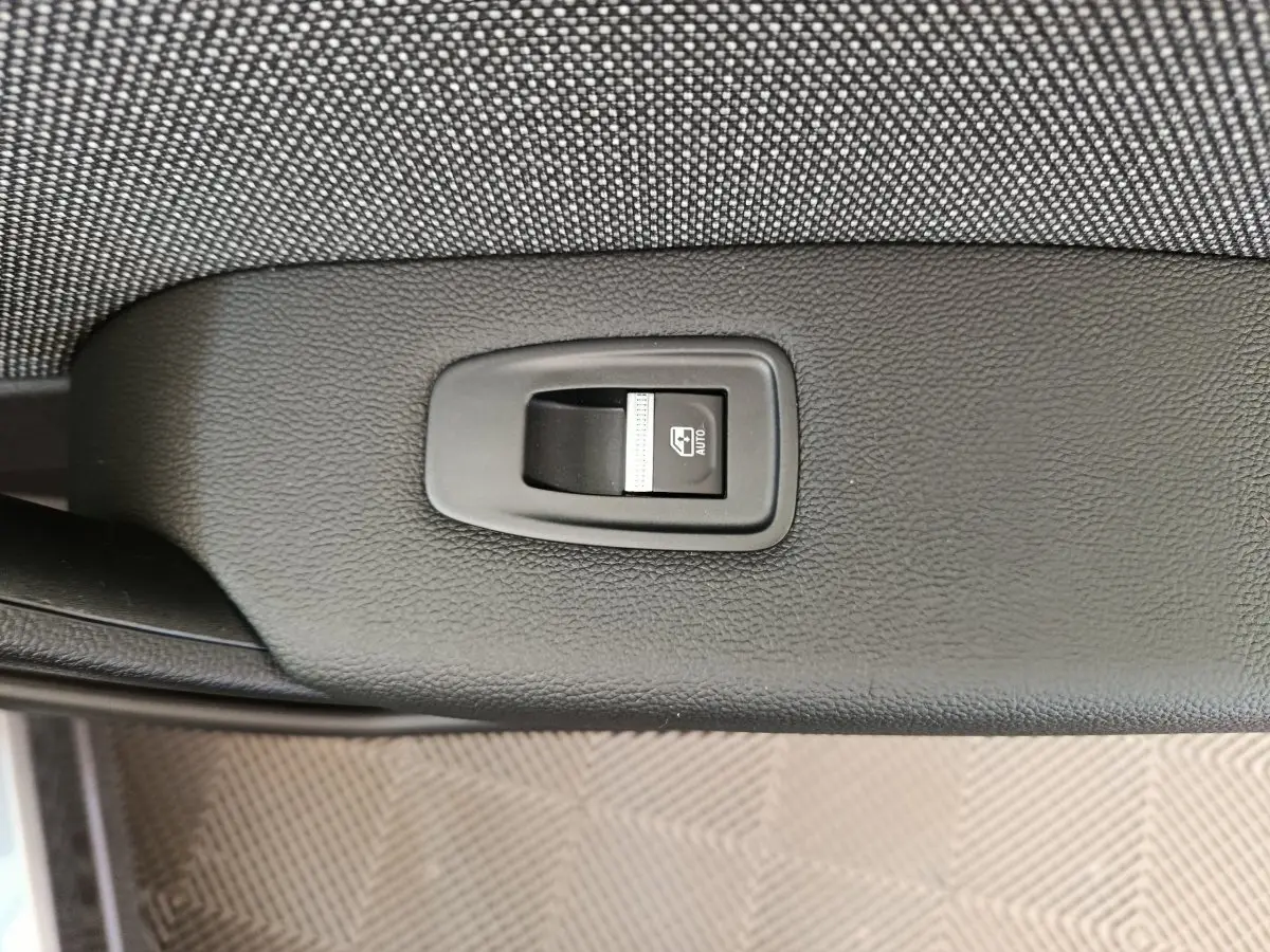 Bouton de commande de lève-vitre automatique sur la portière intérieure noire d'un Renault Captur gris foncé 2025.