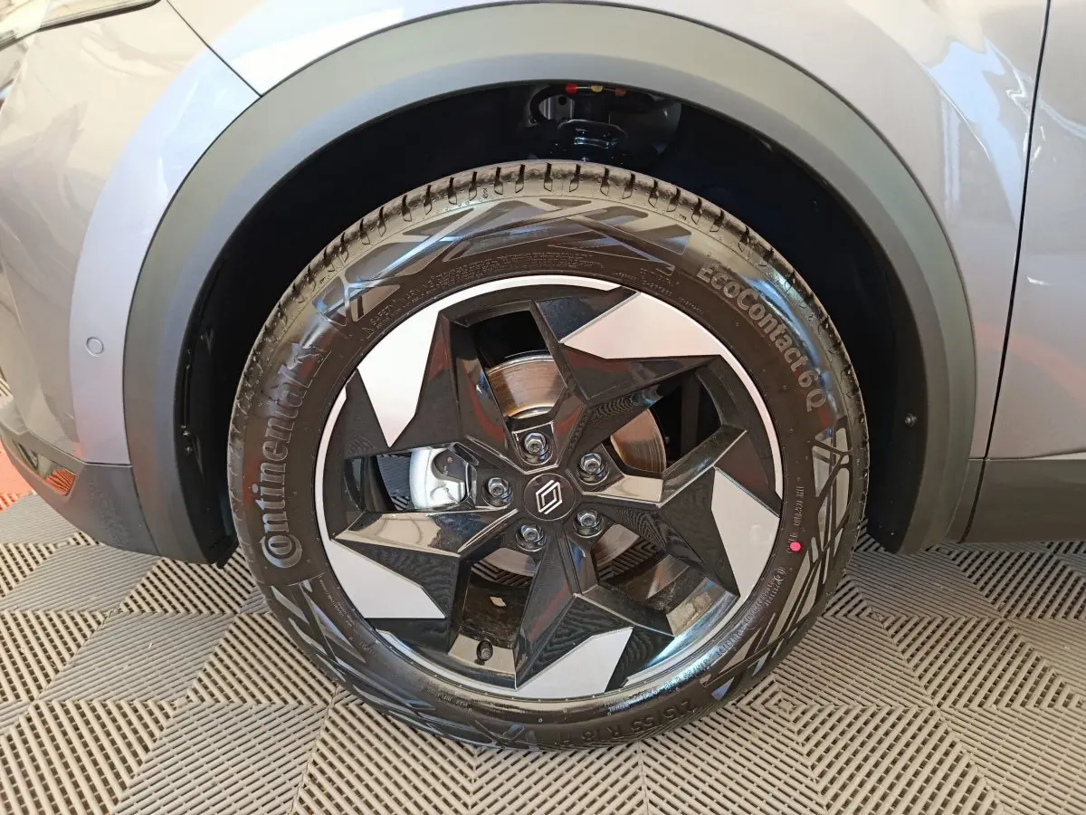 Gros plan sur la roue avant droite du Renault Captur gris foncé, mettant en valeur la jante noire au design étoilé.