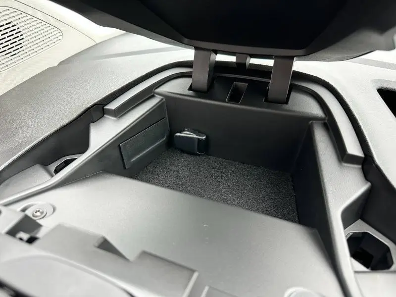 Compartiment de rangement intérieur ouvert en plastique noir dans un Nissan Townstar électrique gris 2024.