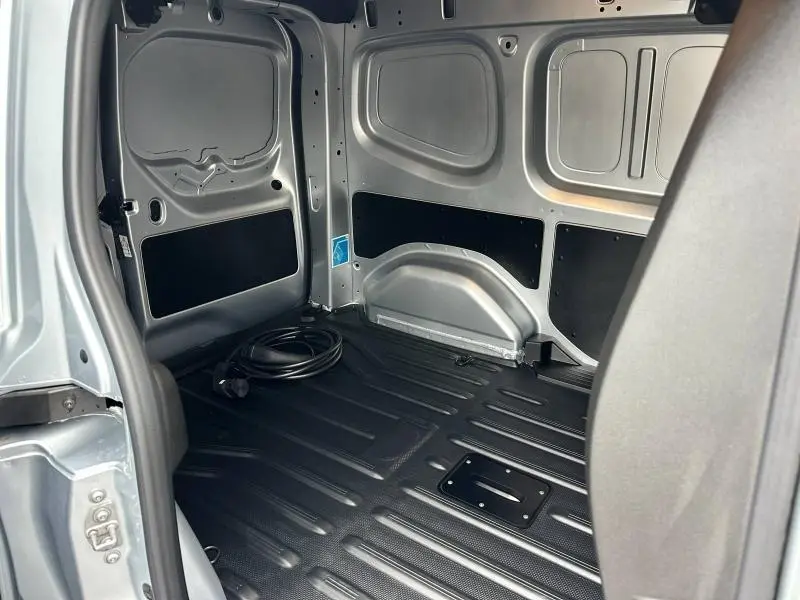 Intérieur de la zone de chargement du Nissan Townstar gris 2024, vue côté droit avec câble de recharge électrique posé au sol.