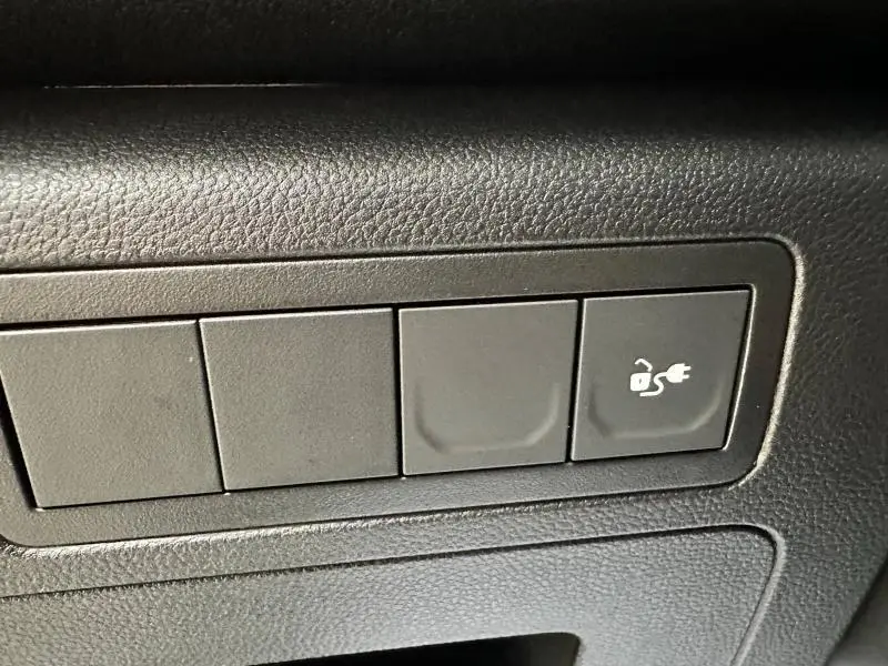 Gros plan sur le bouton de recharge électrique sur la planche de bord noire du Nissan Townstar gris 2024.