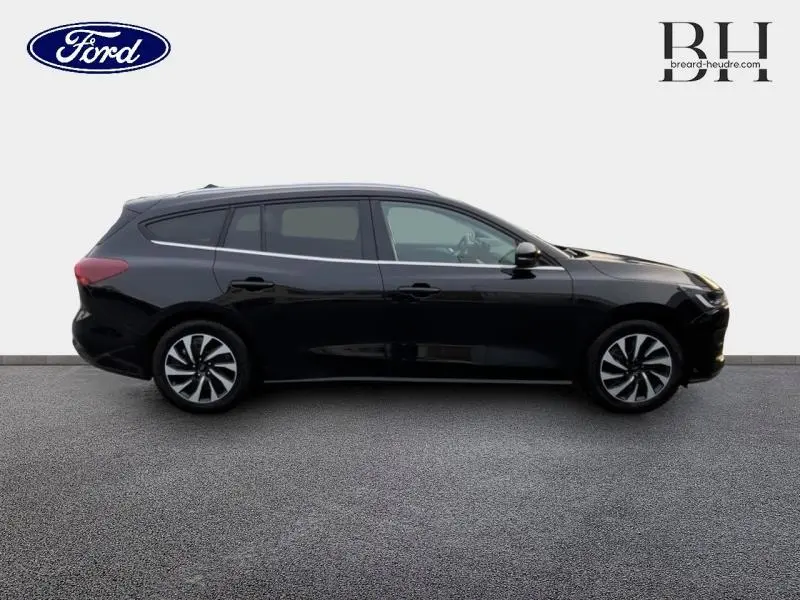 Vue de profil côté gauche d'une Ford Focus SW 2024 noir Agate métallisé avec jantes alliage et vitres surteintées.