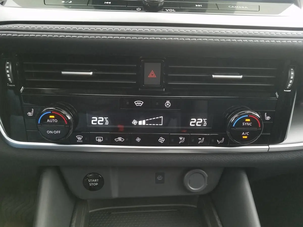 Vue rapprochée du tableau de bord noir du Nissan Qashqai 2025, montrant la climatisation automatique bi-zone et les commandes digitales.