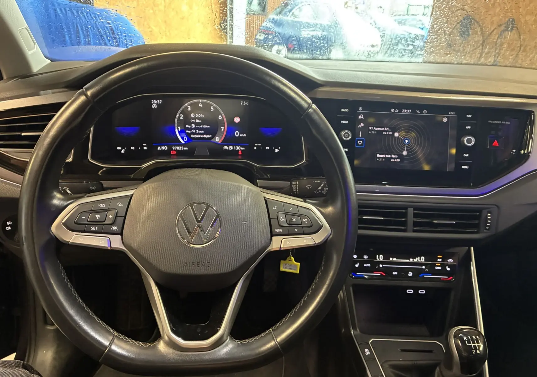 Vue intérieure centrée sur le volant multifonctions noir et le tableau de bord digital d'une Volkswagen Polo gris 2022.