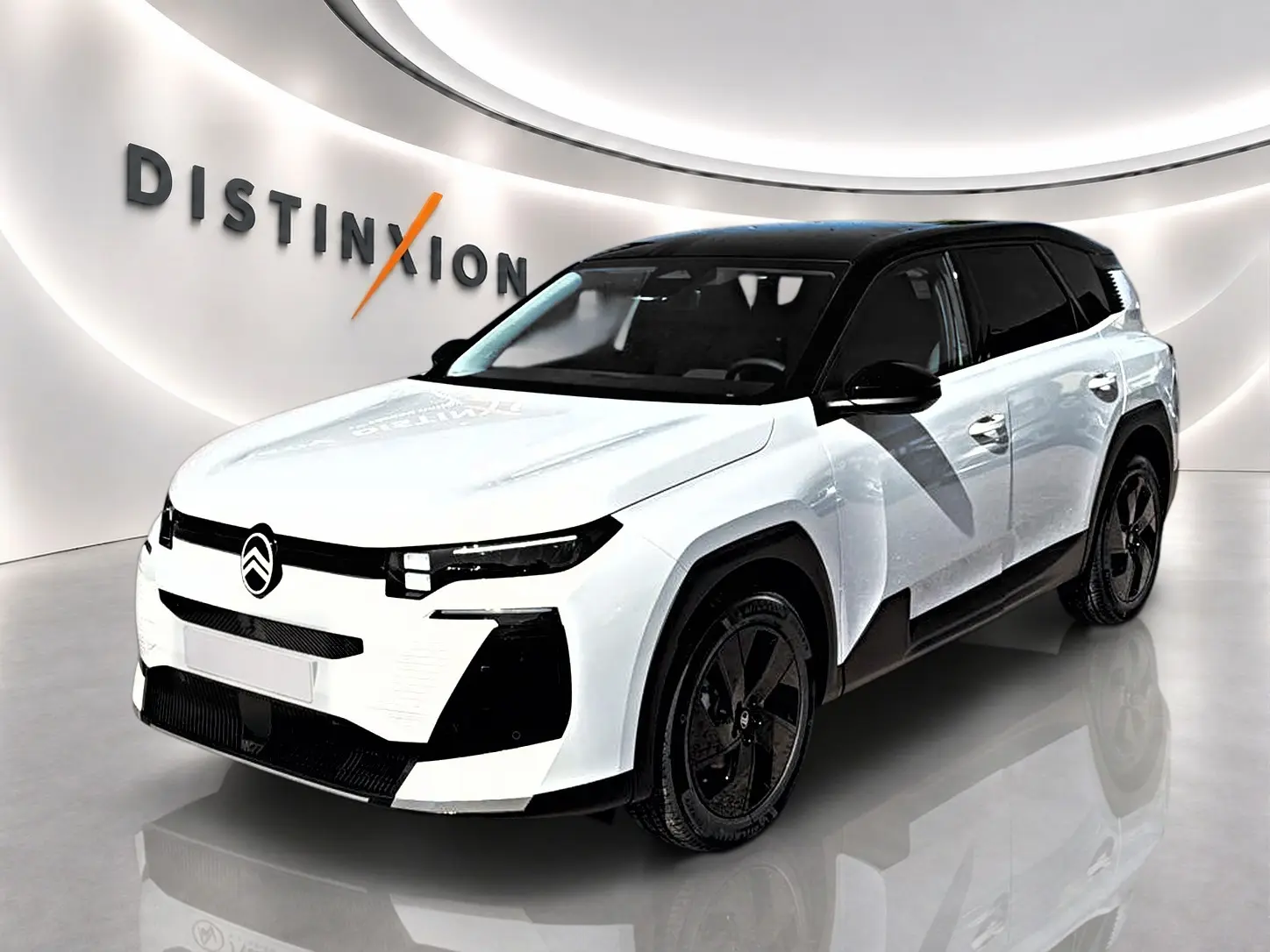 Vue 3/4 avant droit du Citroën C5 Aircross blanc à toit noir avec jantes alliage noires dans un showroom.