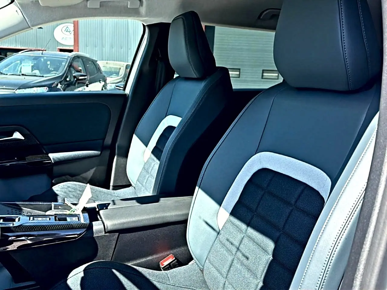 Vue intérieure côté droit montrant les sièges avant bi-matière noirs et gris du Citroën C5 Aircross 2026 hybride.