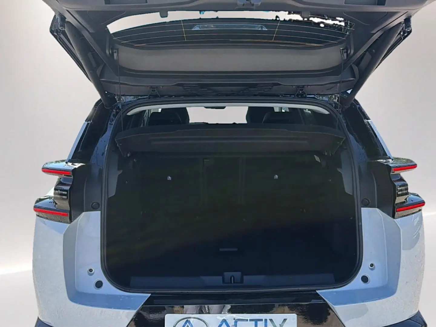 Vue arrière du Citroën C5 Aircross hybride blanc et noir avec coffre ouvert et hayon relevé, feux arrière LED visibles.