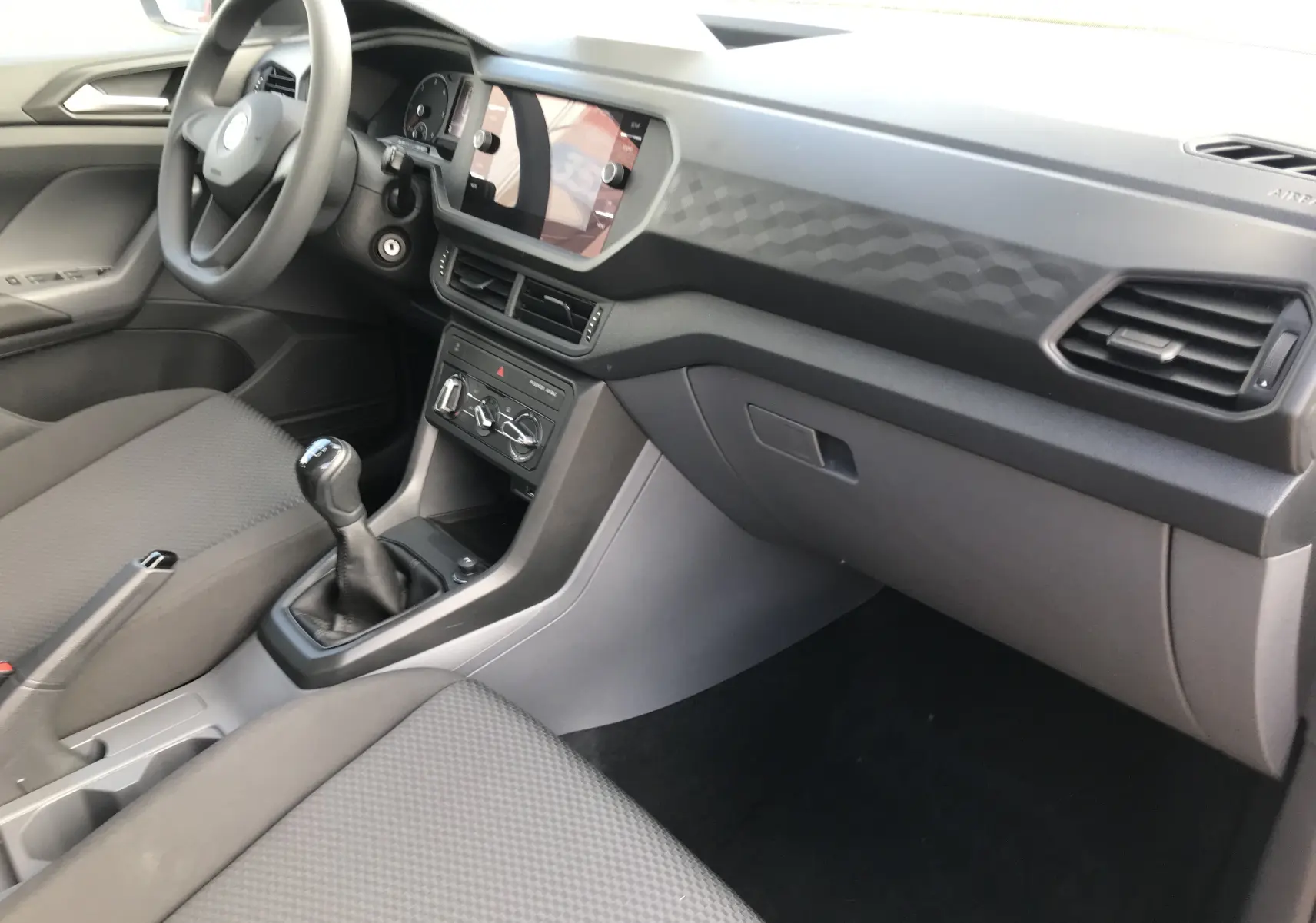 Intérieur côté passager du Volkswagen T-Cross 2020 gris Limestone, avec tableau de bord texturé et levier de vitesse manuel.