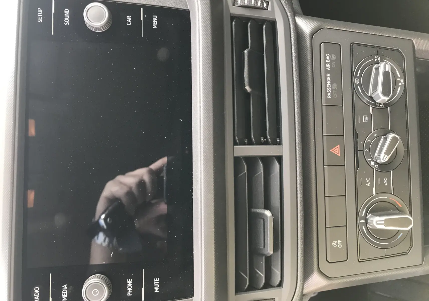 Tableau de bord du Volkswagen T-Cross 2020 avec écran tactile noir et commandes de climatisation grises en gros plan.