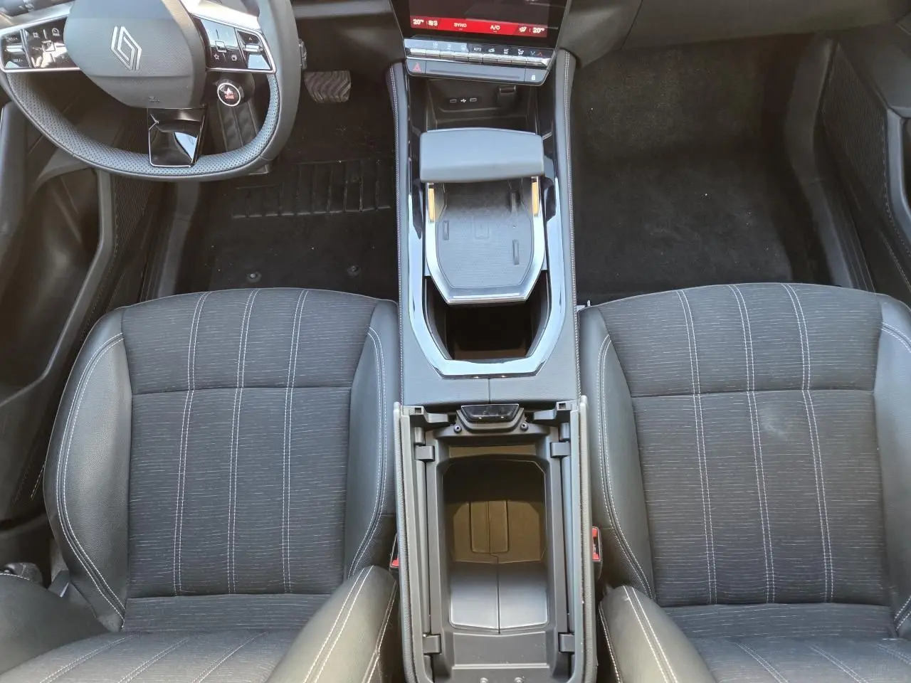 Vue intérieure plongeante sur les sièges avant noirs et la console centrale ouverte du Renault Austral E-Tech 2025.