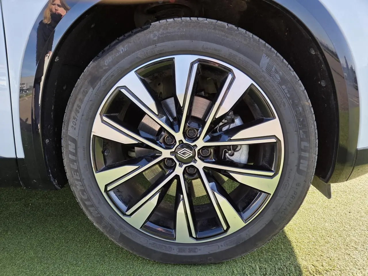 Gros plan sur la jante alliage 19 pouces Komah diamantée noire du Renault Austral blanc nacré avec toit noir.