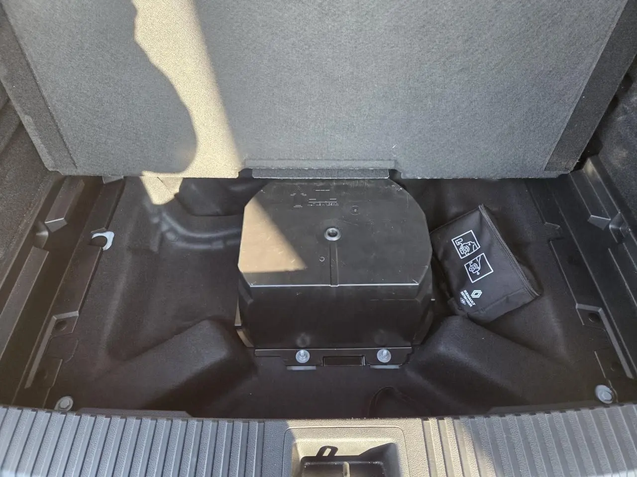 Vue plongeante sur le coffre du Renault Austral blanc nacré, montrant le rangement sous plancher avec trousse de secours.