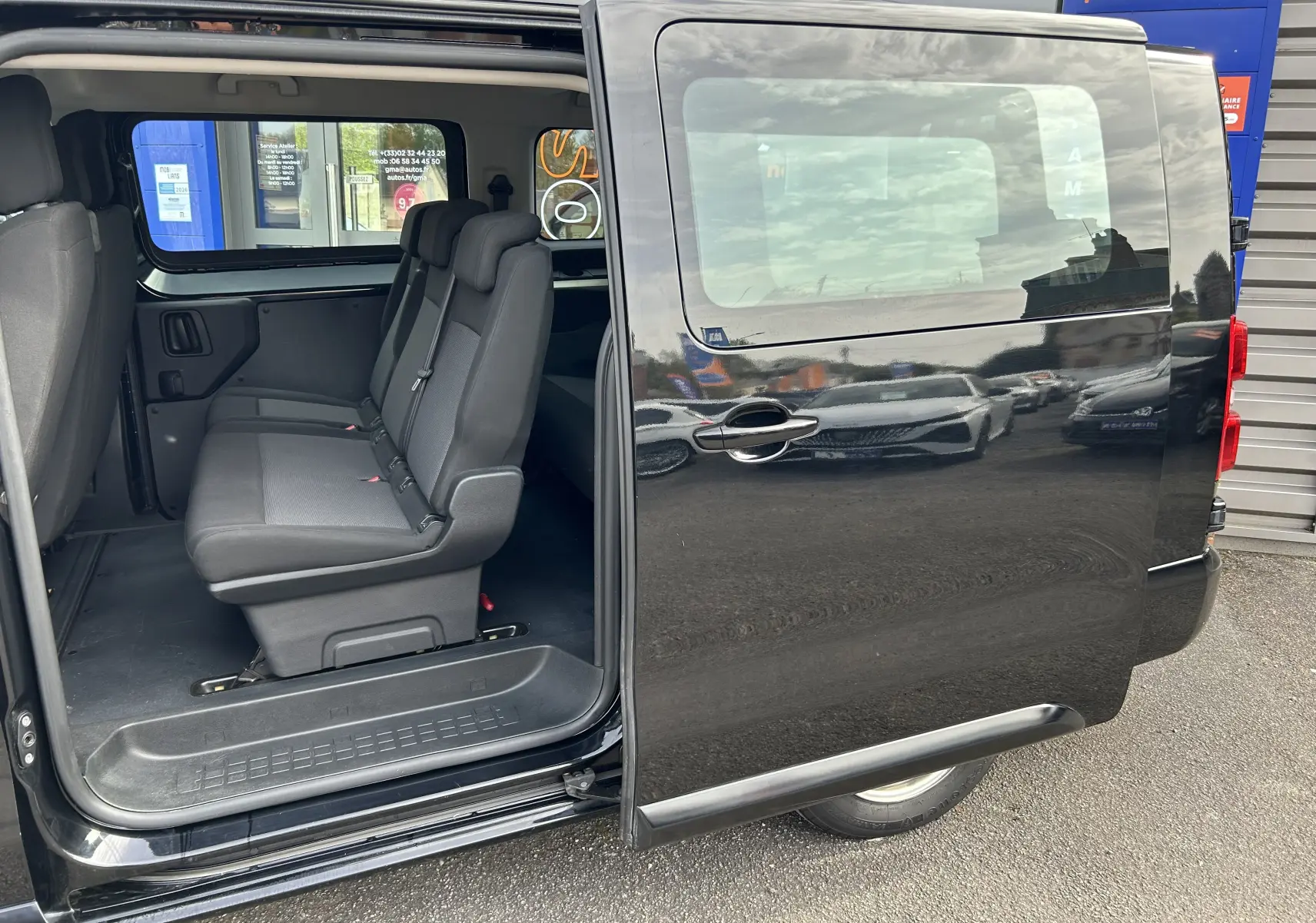 Vue latérale droite d’un Opel Vivaro Combi noir 2022 avec porte coulissante ouverte montrant les sièges passagers en tissu.