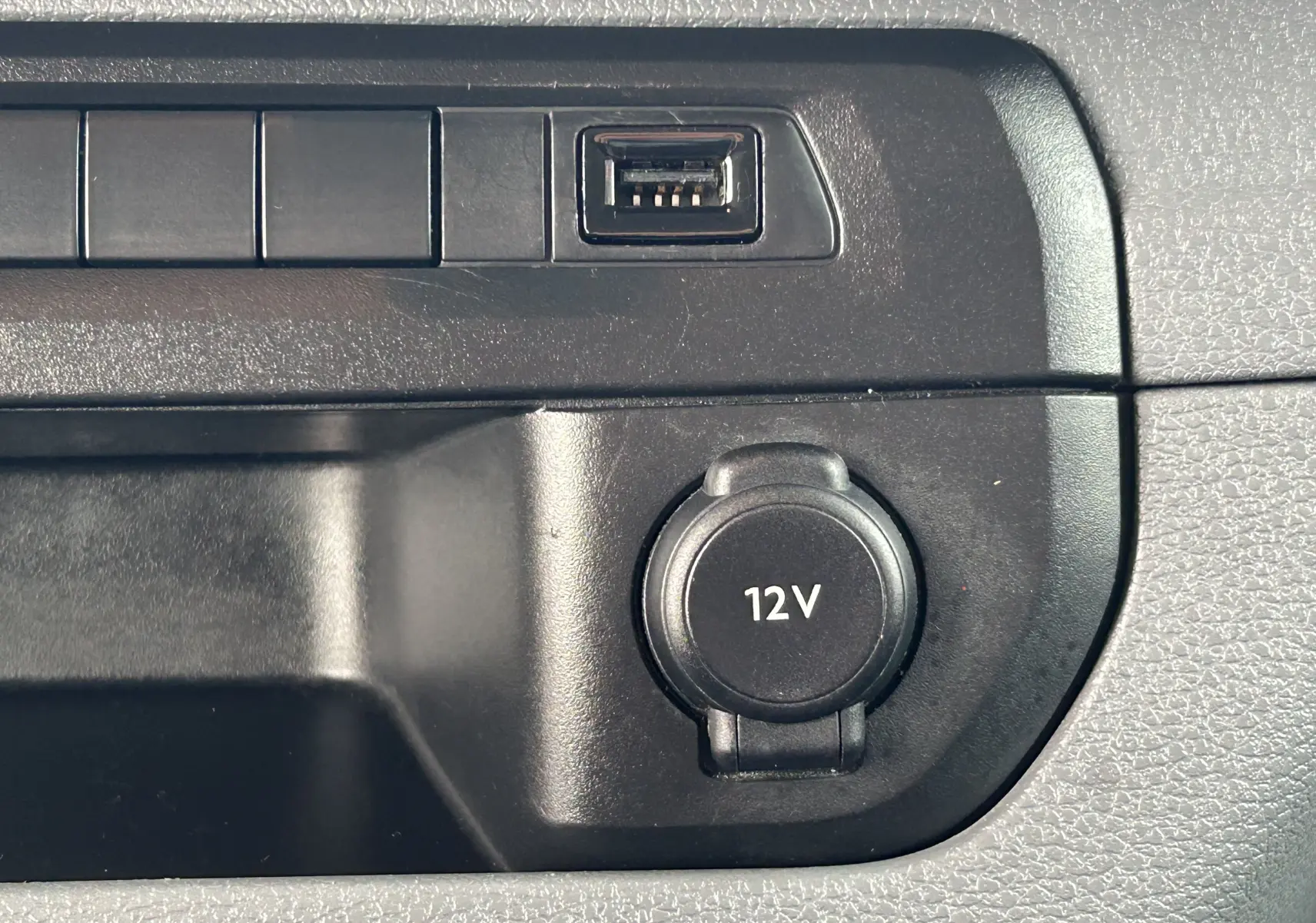 Gros plan sur la prise 12V et port USB intégrés dans la console intérieure noire de l’Opel Vivaro Combi.