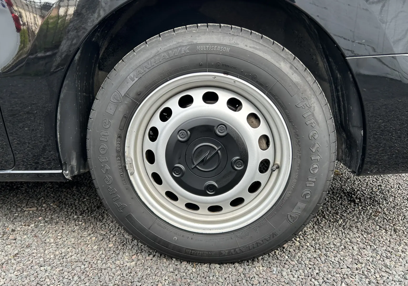 Gros plan sur la roue avant gauche noire d’un Opel Vivaro Combi 2022 avec jante acier et pneu Firestone.