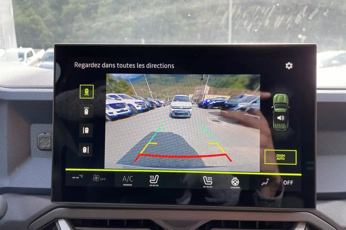 Écran de caméra multiview montrant la vue arrière d’un Dacia Duster vert cèdre en stationnement.