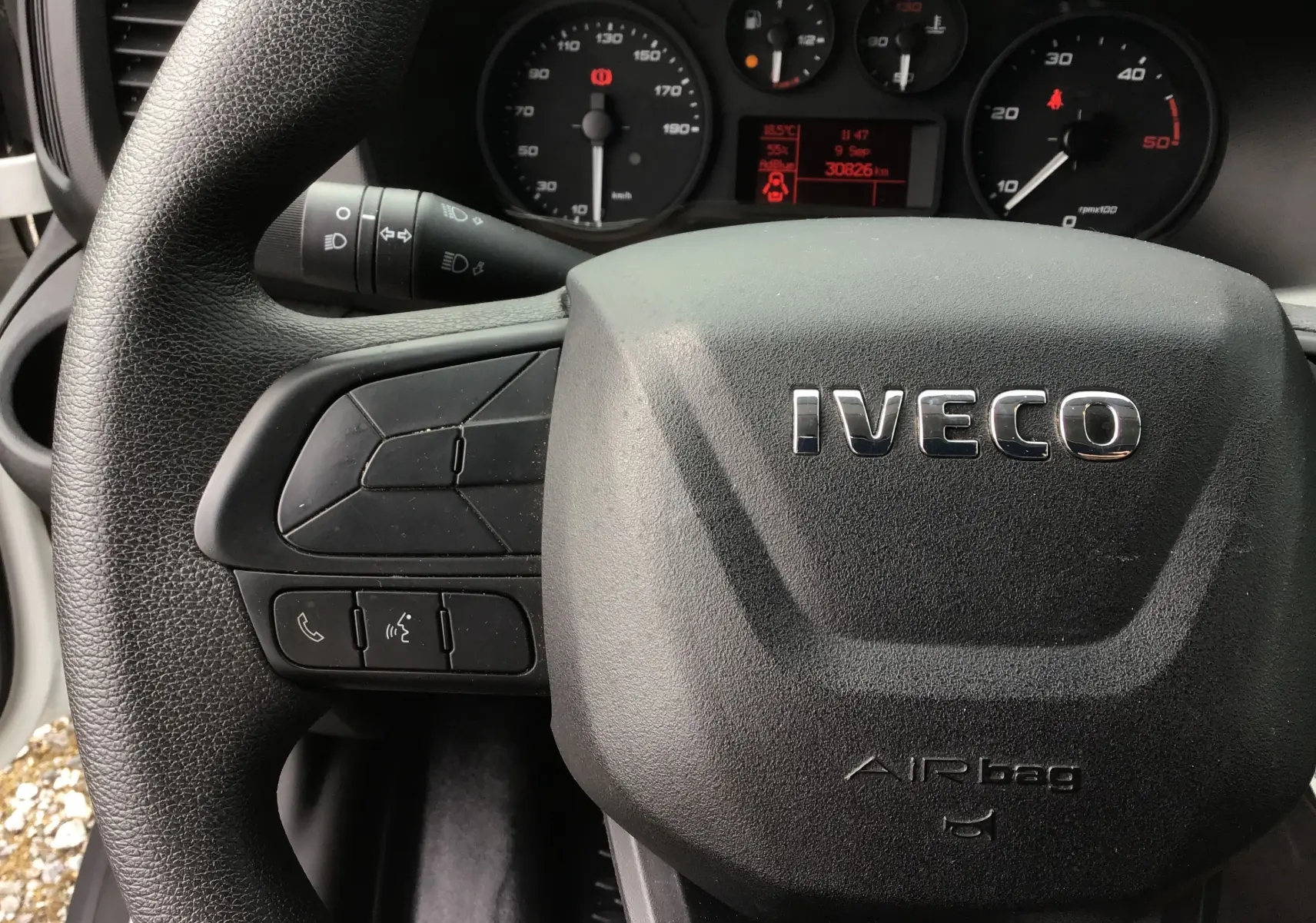 Gros plan sur le volant noir IVECO et le tableau de bord du Daily Chassis Cabine blanc, avec commandes intégrées visibles.