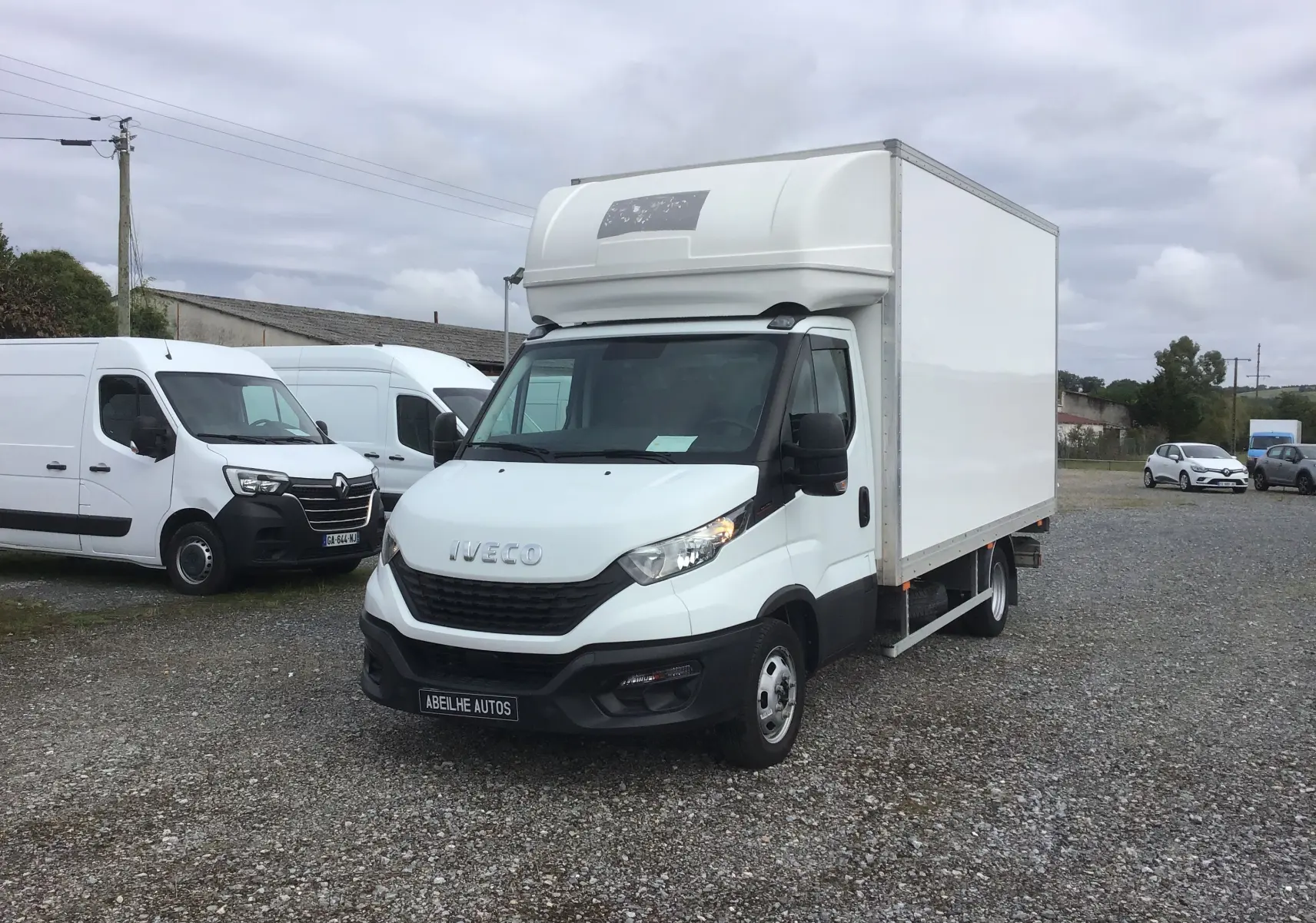 Camion Iveco Daily Chassis Cabine blanc vu en 3/4 avant droit avec caisse fermée et hayon arrière sur parking.