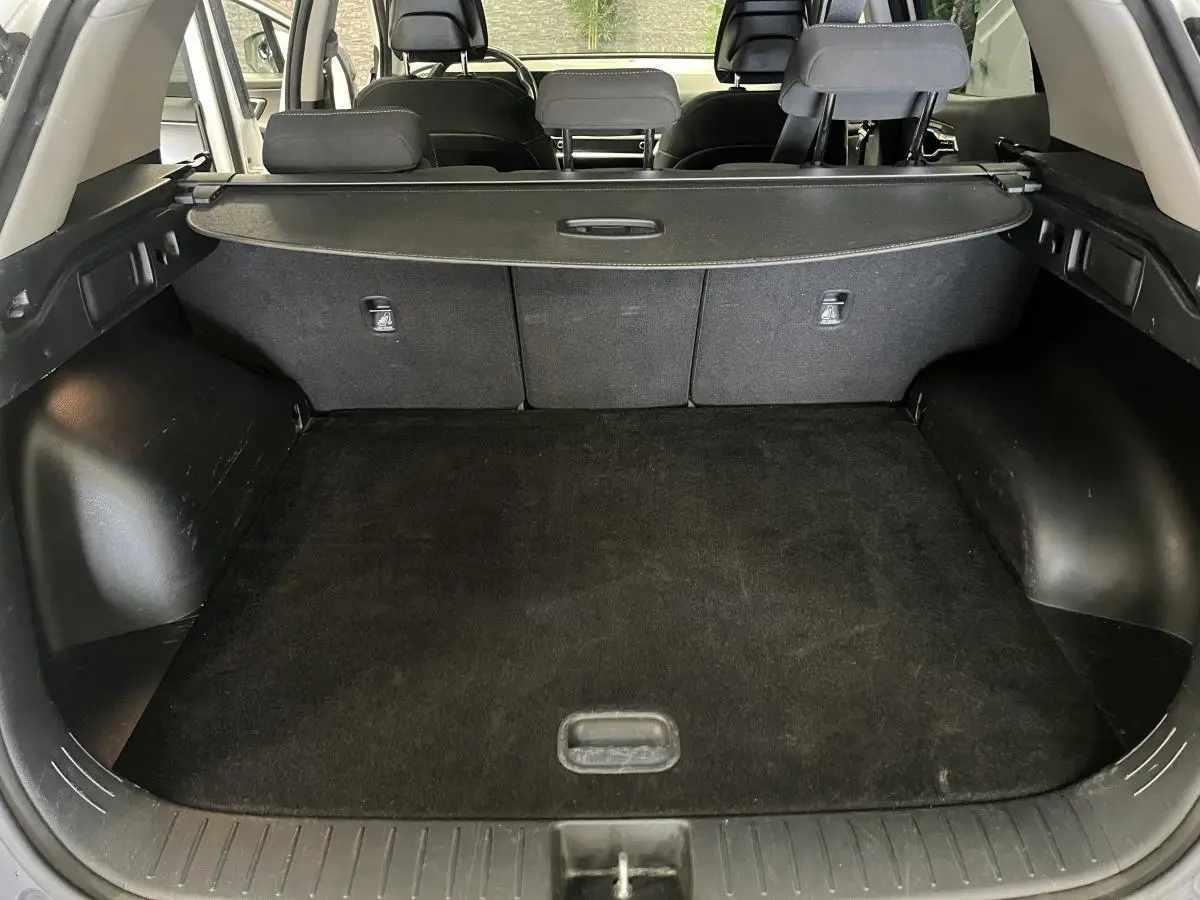 Coffre ouvert du Kia Sportage blanc 2022, montrant l'espace de chargement et la plage arrière noire.