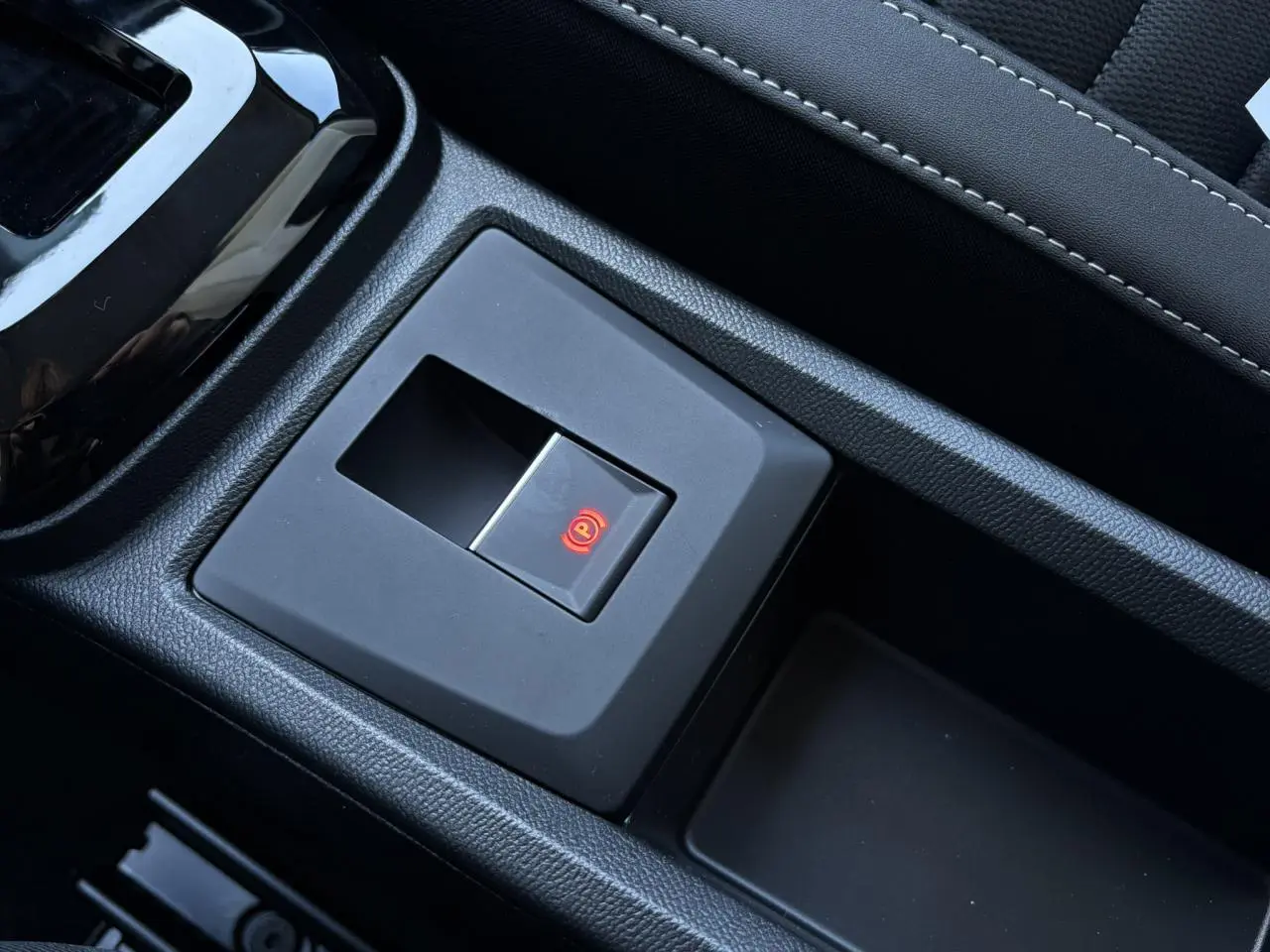 Bouton de frein de stationnement électrique allumé sur la console centrale noire du Citroën C3 Aircross 2025.
