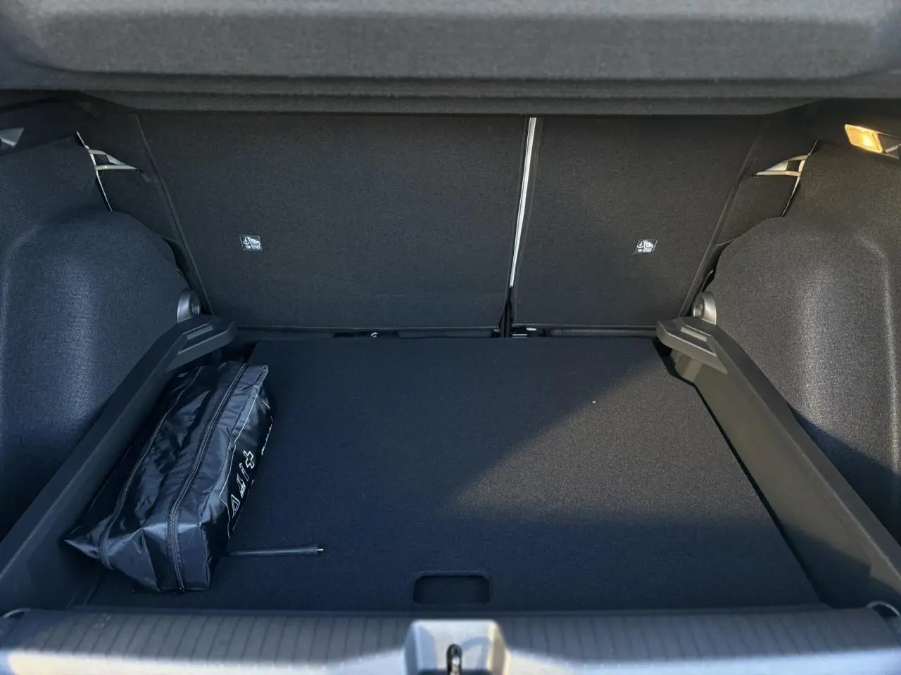 Coffre spacieux noir du Citroën C3 Aircross 2025 avec sac de secours visible sur le côté gauche.