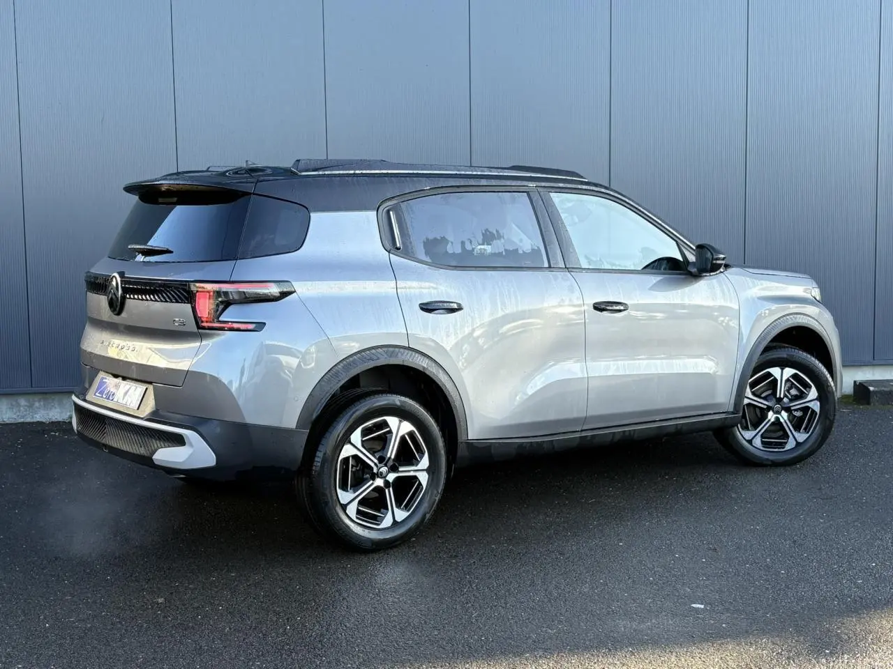 Vue 3/4 arrière droite d'un Citroën C3 Aircross gris Mercury avec toit noir et jantes alliage 17 pouces.