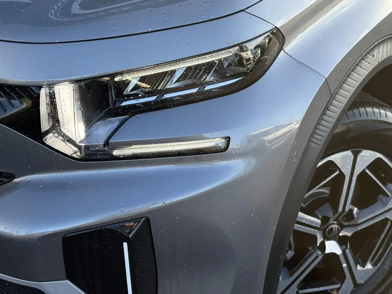 Gros plan sur l'avant droit gris Mercury du Citroën C3 Aircross 2025, mettant en valeur le phare LED et la jante alliage.