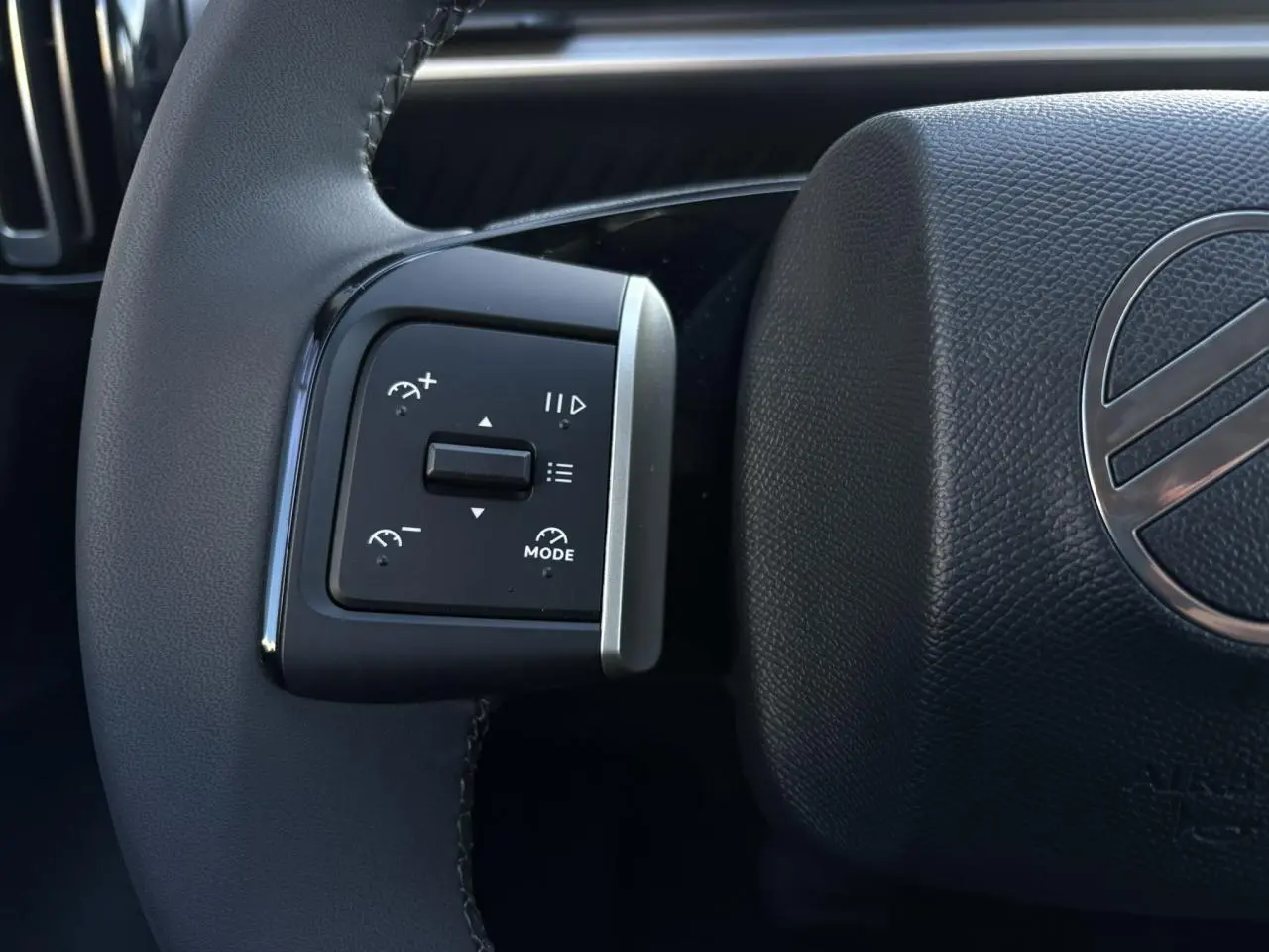 Gros plan sur les commandes multifonctions à gauche du volant noir texturé du Citroën C3 Aircross gris Mercury 2025.
