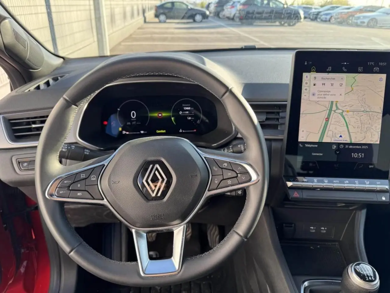 Vue intérieure centrée sur le volant Renault d’un Captur II 2025, avec tableau de bord numérique et écran tactile GPS.