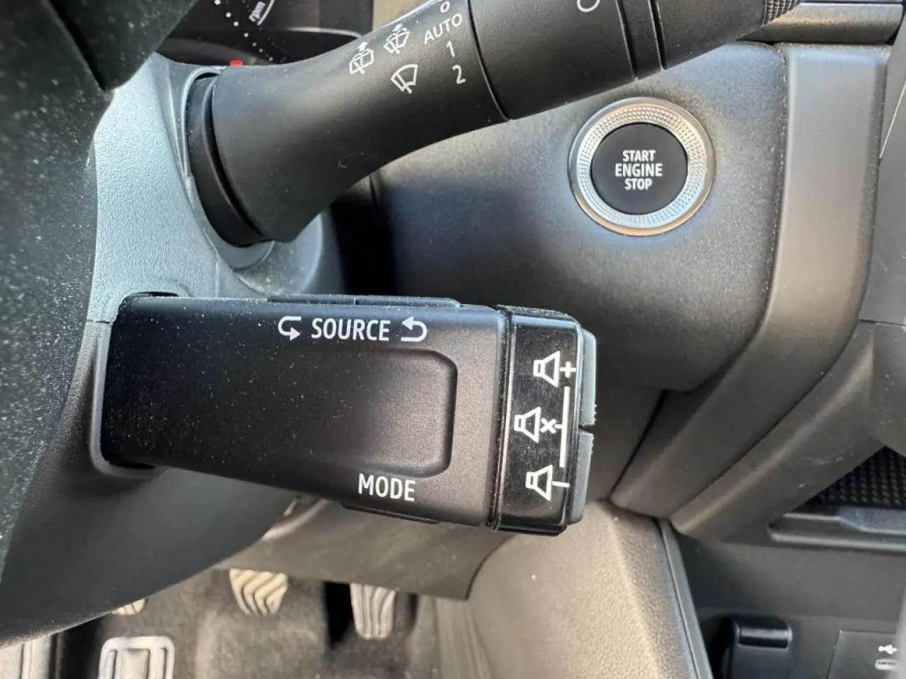 Gros plan sur la commande au volant et bouton Start Engine Stop du Renault Captur II rouge flamme avec intérieur noir.