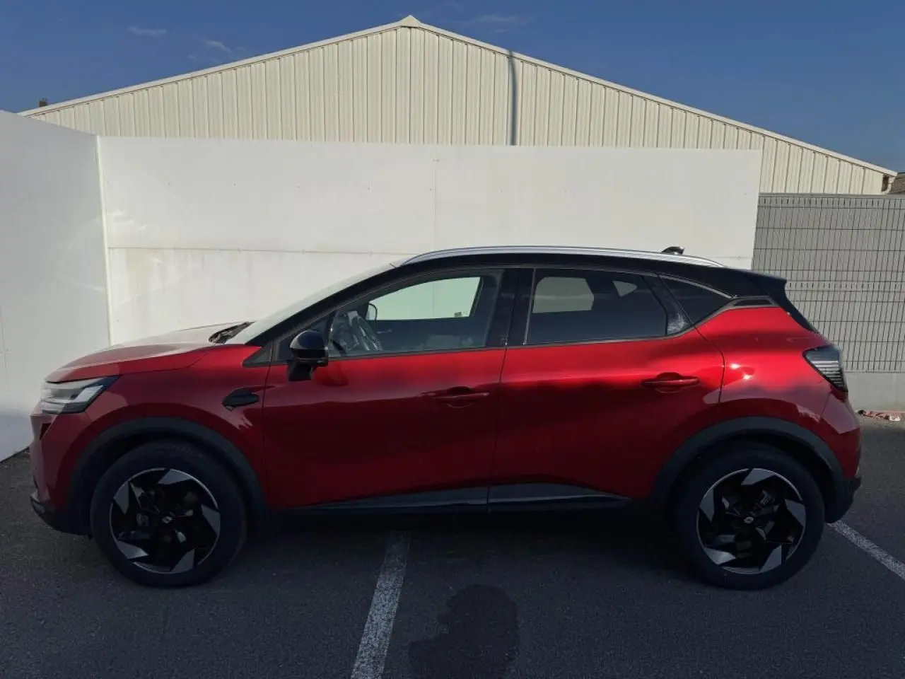 Profil côté gauche du Renault Captur II rouge flamme avec toit noir étoilé et jantes aluminium noires.
