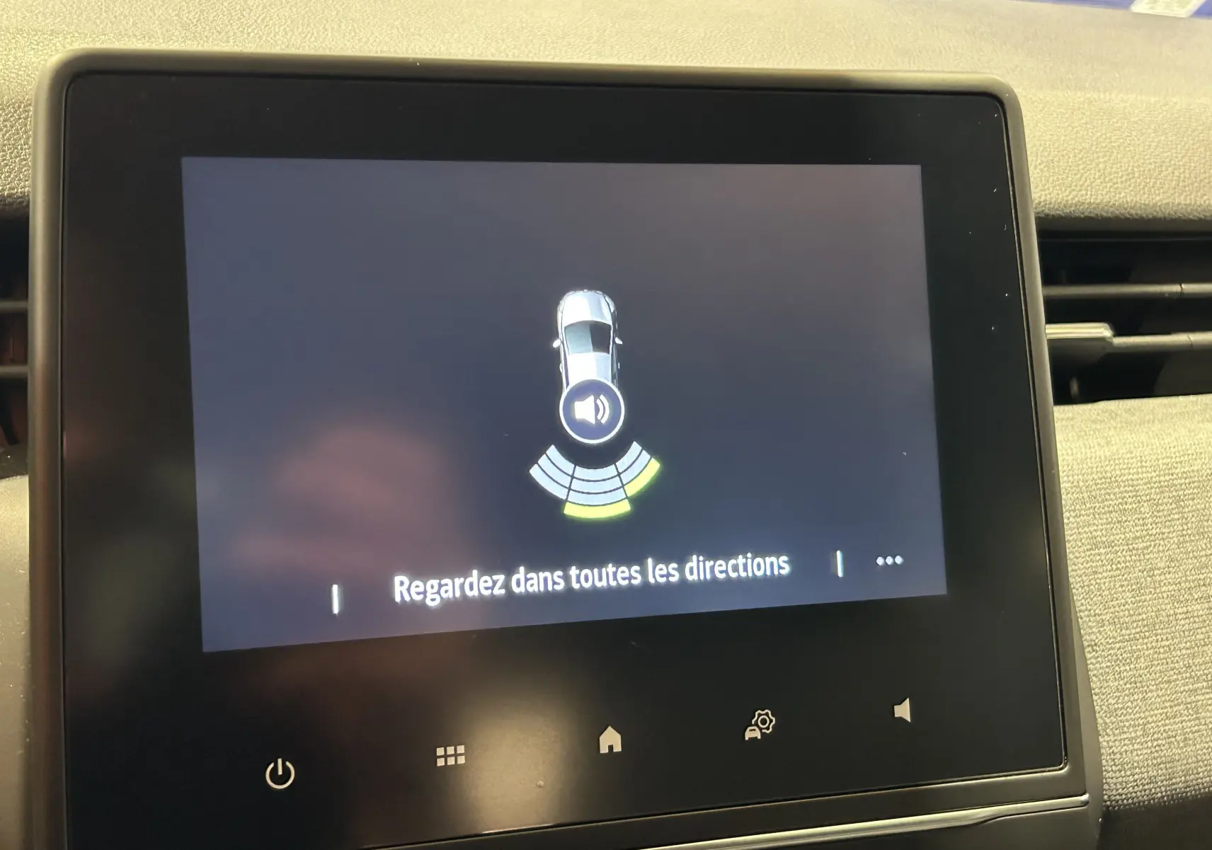 Écran tactile central de Renault Clio V blanc affichant l'alerte radar de recul avec message "Regardez dans toutes les directions".