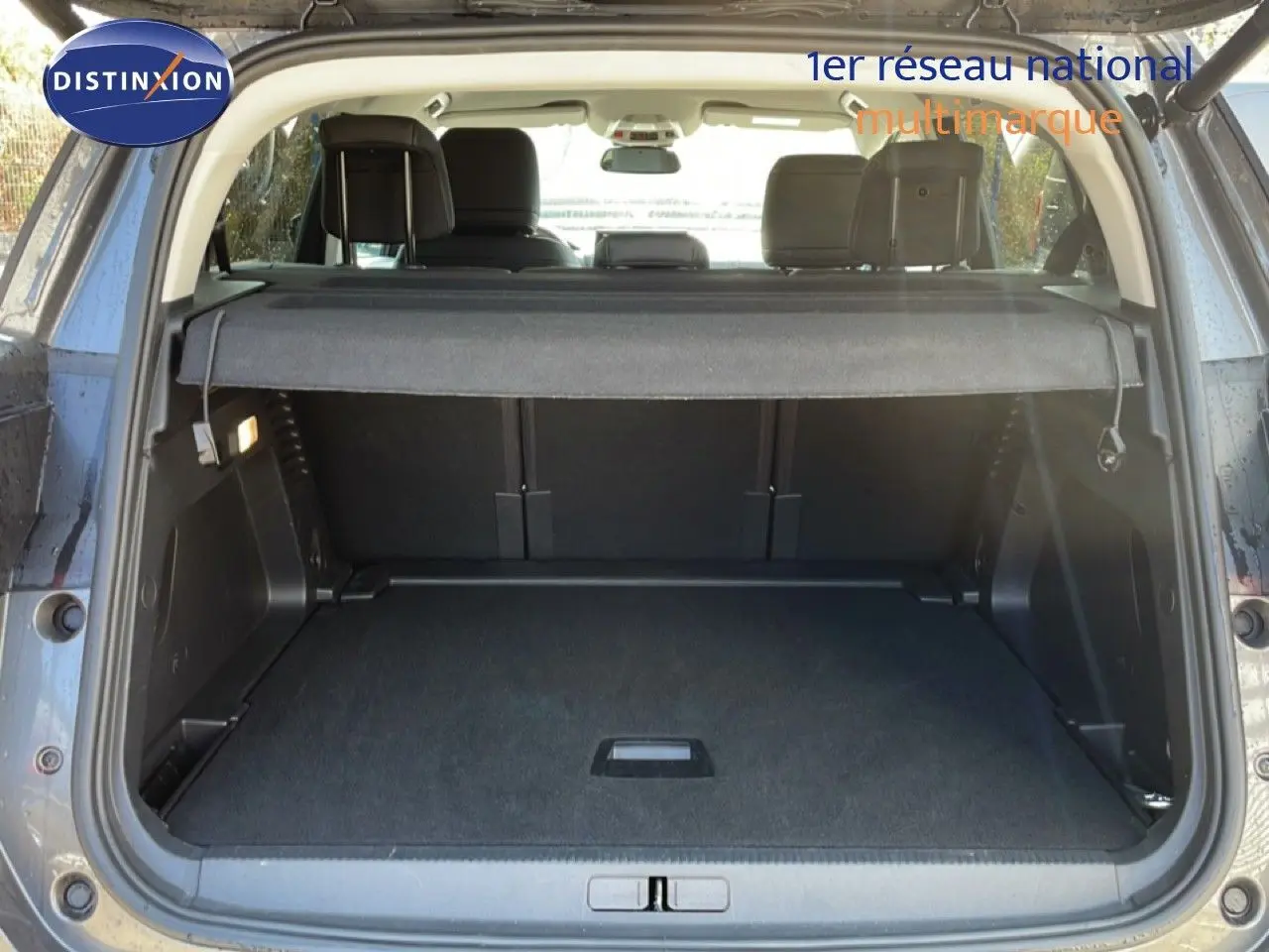 Coffre ouvert vu de l’arrière d’un Citroën C5 Aircross gris platinium métal, avec cache-bagages et sièges arrière visibles.
