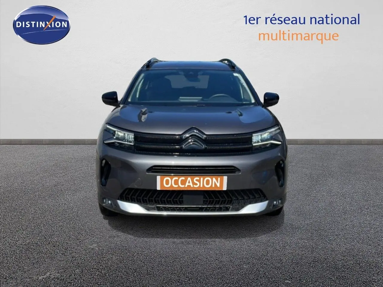 Vue frontale d'un Citroën C5 Aircross gris platinium métal 2025 avec calandre distinctive et feux LED allumés.