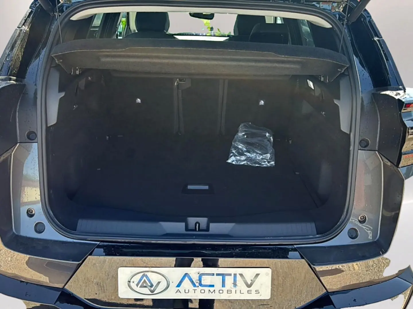 Coffre ouvert vue arrière d’un Citroën C5 Aircross gris platinium avec hayon électrique et plancher de coffre mobile.