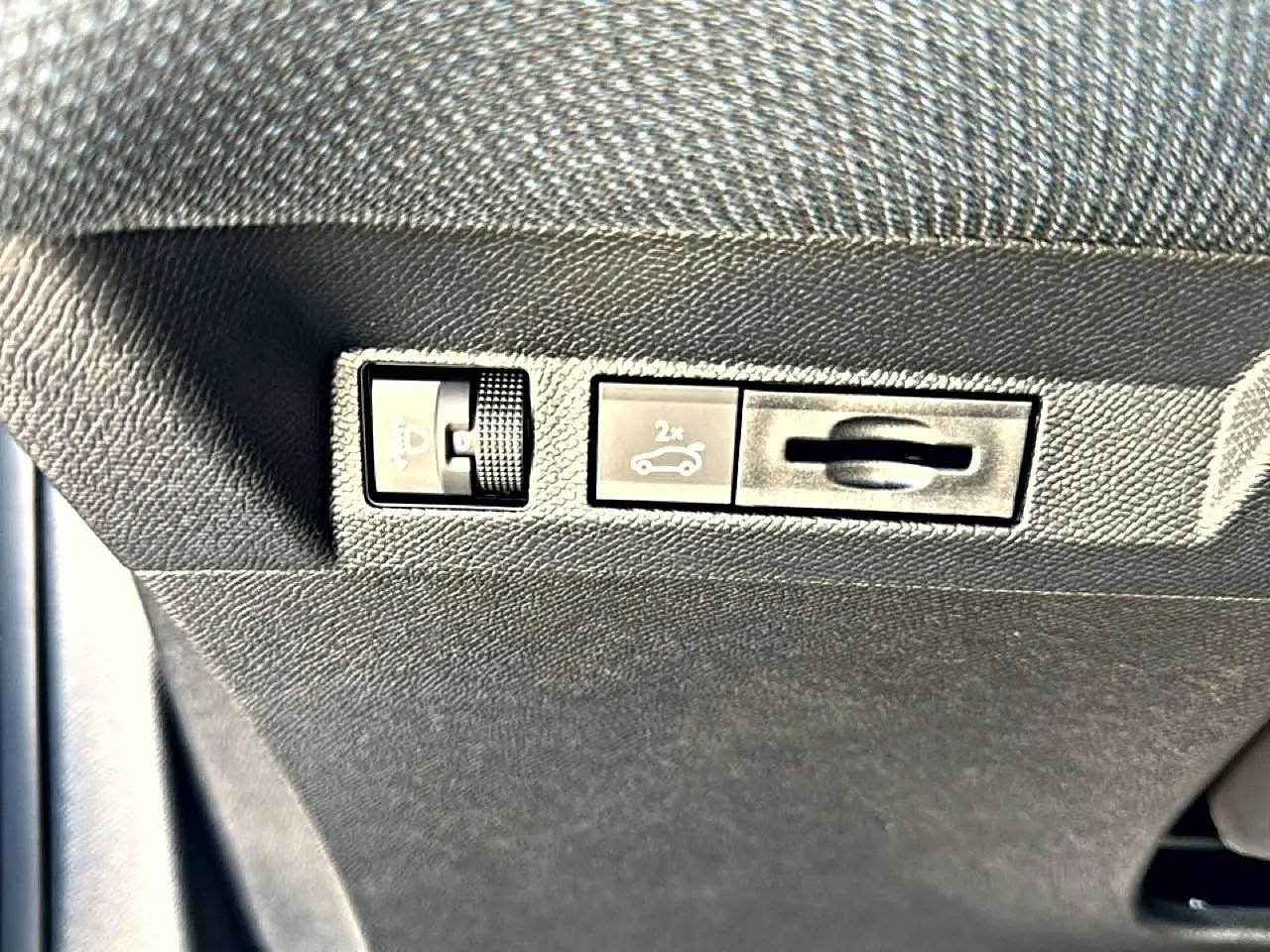 Gros plan sur les commandes sous le tableau de bord du Citroën C5 Aircross gris platinium, bouton ouverture hayon visible.